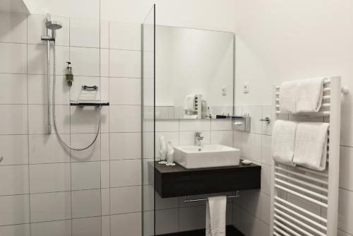 a white bathroom with a sink and a shower at UHU Gästehaus Superior in Cologne