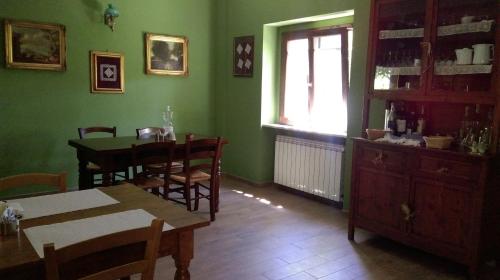 uma sala de jantar com paredes verdes e uma mesa e cadeiras em Il GIARDINACCIO Agriturismo em LʼAquila