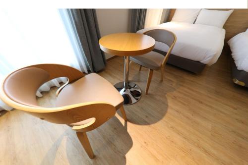 a hotel room with a bed and a table and chairs at Hotel Rest Seogwipo in Seogwipo