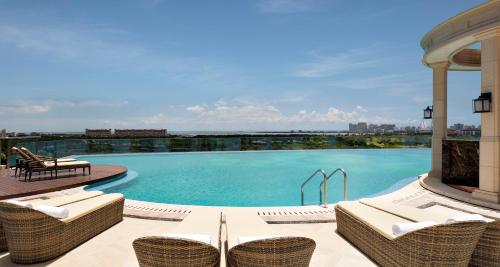 a swimming pool with wicker chairs on a patio at The Langham Haikou in Haikou