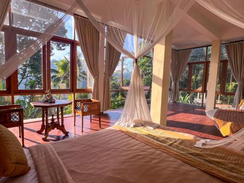 a bedroom with a bed and a table and windows at Made Punia's Hidden Jungle Ubud in Ubud