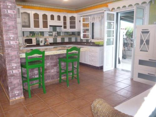 eine Küche mit grünen Barhockern in einem Zimmer in der Unterkunft Abades Chalet in La Listada