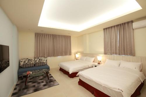 ein Hotelzimmer mit 2 Betten und einem Sofa in der Unterkunft Sun Light Guesthouse in Hualien