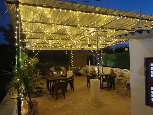 a patio with tables and chairs under a canopy with lights at De Dreams beach in Puducherry