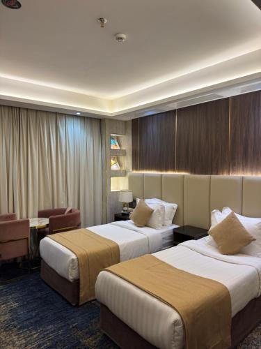 a hotel room with two beds and a desk at Sparrow Apartments Hotel in Jeddah