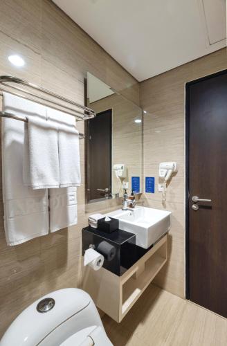 a bathroom with a white toilet and a sink at Fairview Hotel by ARTOTEL in Jakarta