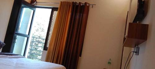 a bedroom with a window with an orange curtain at Hotel O The Honey Guest House in Haldwāni