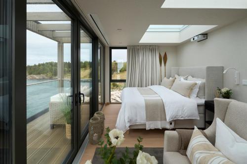 een slaapkamer met een bed en een balkon met een zwembad bij Hideaway Herdla luxurious cabins 15 m above the sea in Herlø