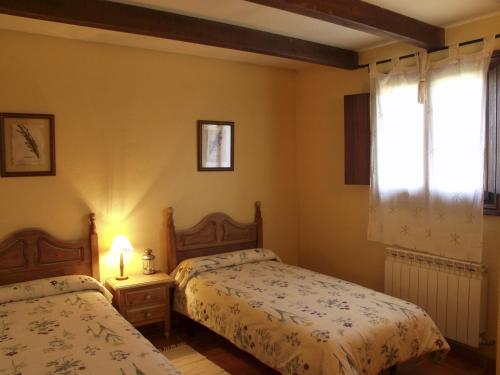 1 dormitorio con 2 camas y ventana en El Mirador de las Candelas, en Linarejos