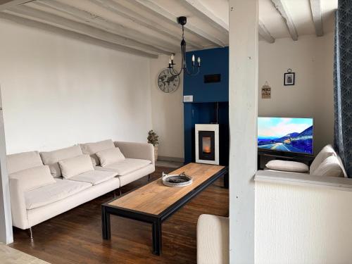 Maison pittoresque et cozy في Bonnat: غرفة معيشة مع أريكة بيضاء وطاولة قهوة