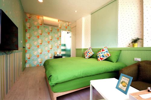 Cama verde en habitación con sofá en 宜蘭羅東迷彩民宿-大吉迷彩 en Luodong