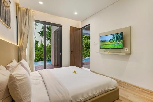 une chambre avec un lit et une télévision sur un mur dans l'établissement JK Bhavana Villas, à Ngemplak