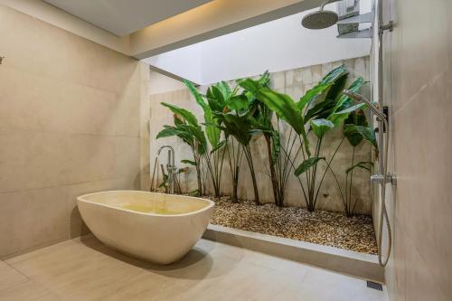 une salle de bain avec une baignoire avec une plante dans l'établissement JK Bhavana Villas, à Ngemplak