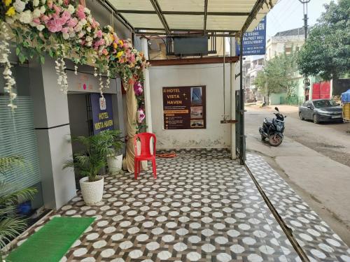 uma entrada para um edifício com uma cadeira vermelha e flores em Hotel Vista Haven em Patna