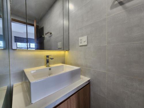 ein Badezimmer mit einem weißen Waschbecken und einem Spiegel in der Unterkunft Lang Retreat Apartment - Resort Pool & Elite Gym in Ho-Chi-Minh-Stadt