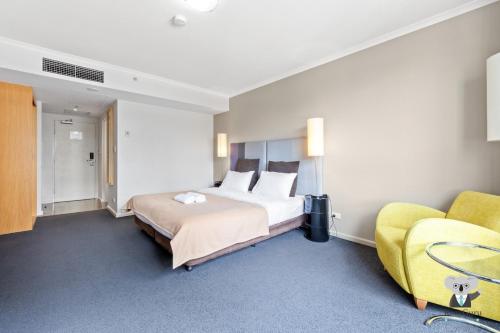 KozyGuru | Parramatta Studio Steps to Shops, Cafés في سيدني: غرفة فندق بسرير واريكة صفراء