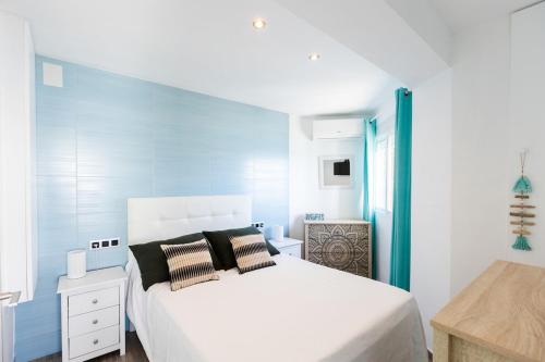 Un dormitorio con una cama blanca y una pared azul. en Front line beach location with stunning ocean view, en Ifach