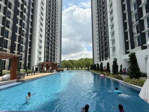 eine Gruppe von Menschen, die in einem großen Schwimmbecken mit Gebäuden schwimmen in der Unterkunft Family-Friendly 3BR Stay I MIRAI Residence, Kajang 2 in Kajang