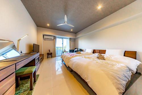 een slaapkamer met een groot bed, een dressoir en een televisie bij 真栄田岬グランブルー 104 in Onna