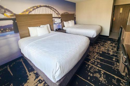 a hotel room with two beds with white sheets at Clarion Pointe Bettendorf - Quad Cities in Bettendorf