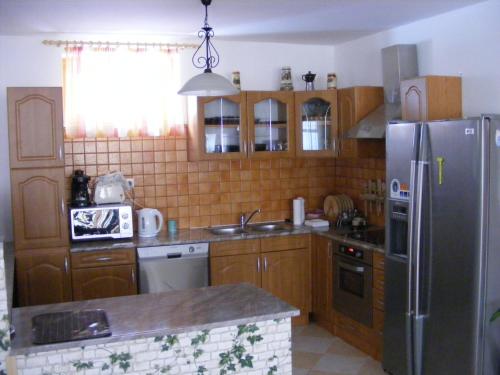 a kitchen with wooden cabinets and a stainless steel refrigerator at Tünde Vendégház in Bernecebaráti