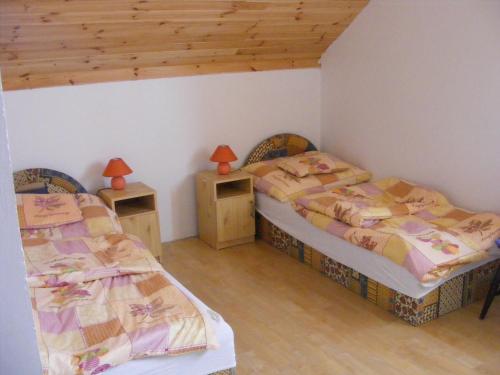 two beds in a room with two tables and two lamps at Tünde Vendégház in Bernecebaráti