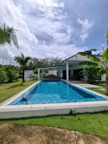 a swimming pool in front of a house at Villa et Bungalow Baan Joan Khao Lak in Khao Lak