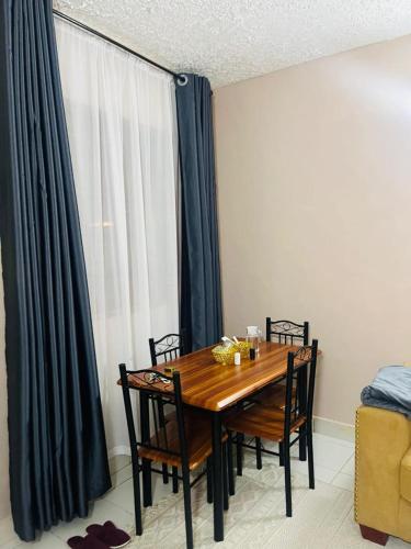 a dining room table with chairs and a window at Fibi Embu Apartments in Embu