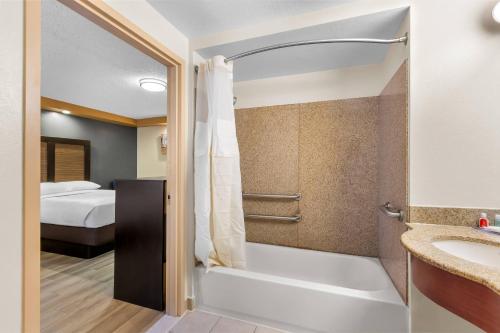 Un baño con ducha y lavabo y una cama. en Econo Lodge Woodbridge, en Iselin