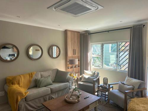 a living room with a couch and a table and mirrors at 20 At Jeanette in Windhoek