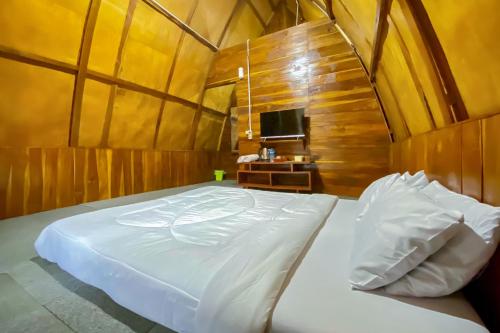 a large white bed in a room with a tv at Embun Lawu Cottage Tawangmangu in Sarangan