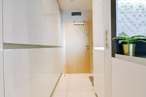 a hallway with white walls and a door with a plant at N9 Studentski Loft in Sofia