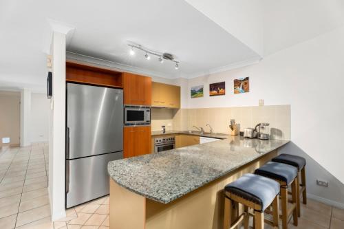 a kitchen with a stainless steel refrigerator and stools at Entire home in Southport Parade Southport in Gold Coast
