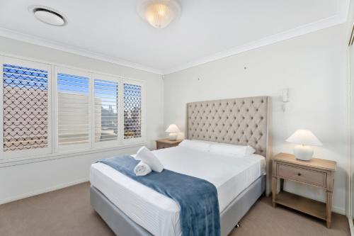 a white bedroom with a bed and a window at Entire home in Southport Parade Southport in Gold Coast