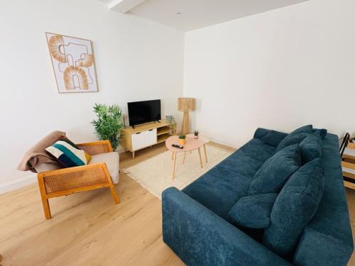 a living room with a blue couch and a tv at Charmant Appartement Rénové l 2 chambres in Réalmont
