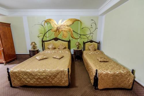 a bedroom with two beds and a flower on the wall at Pensiunea Paradis in Râmnicu Vâlcea