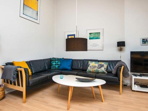 a living room with a black couch and a table at 6 person holiday home in Ringkøbing in Ringkøbing