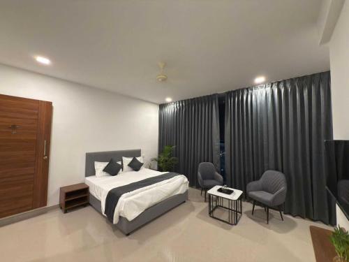 a bedroom with a bed and two chairs in it at Hotel O Fortune Palace in Hinjewadi