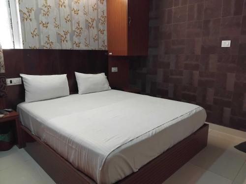 a bed with white sheets and pillows in a room at Hotel O Kilambakkam New Bus Terminal Formerly TAD Homes in Urapakkam