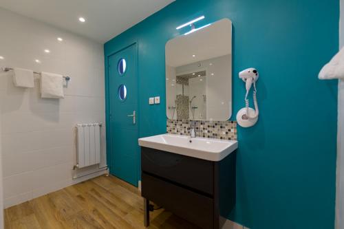 a bathroom with a sink and a blue wall at Citotel Le Regina Bordeaux Gare Saint-Jean in Bordeaux