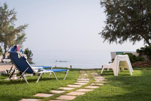 a couple of lawn chairs and a table and chairs on the grass at Hermes Beach Front in Stalos