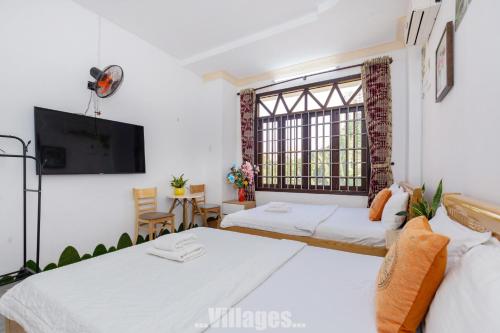 two beds in a room with a tv and a window at Villa Bãi Sau Vũng Tàu Free SUB - Xe Máy in Vung Tau