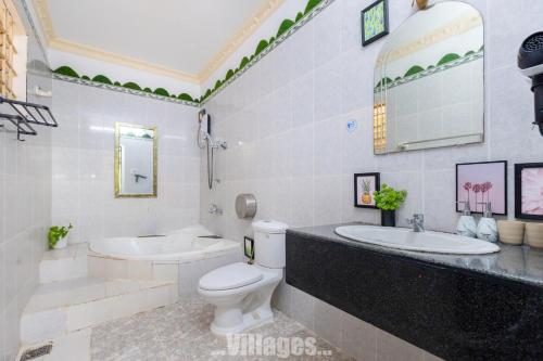 a white bathroom with a toilet and two sinks at Villa Bãi Sau Vũng Tàu Free SUB - Xe Máy in Vung Tau
