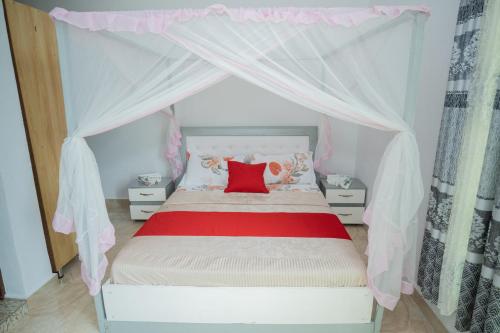 a bedroom with a canopy bed with a red pillow at The city Block Apartment in Bujumbura