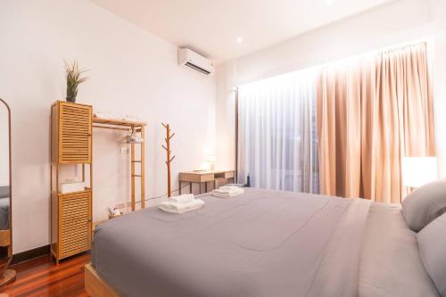 une chambre blanche avec un grand lit et une fenêtre dans l'établissement Minimal House Maximum Happiness, à Thung Maha Mek