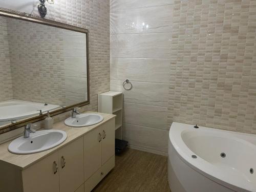 a bathroom with two sinks and a tub and a mirror at Magical Desire in Bragadiru