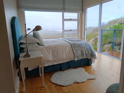 Un dormitorio con una cama y una ventana grande en Tranquility Heights, en Pringle Bay