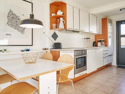 a kitchen with white cabinets and a table with chairs at 5 person holiday home on a holiday park in Gudhjem in Gudhjem