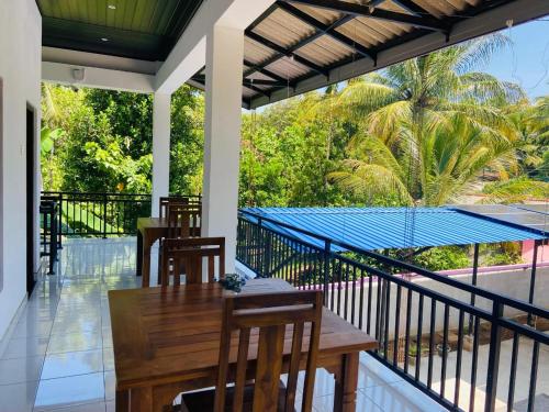 Un porche con una mesa y sillas en un balcón. en Lodge in Resolute, en Dambulla
