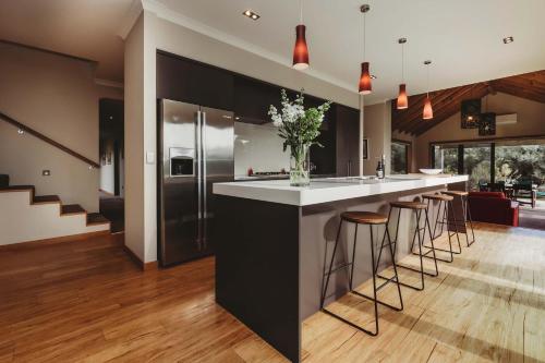 a kitchen with a counter and bar with stools at Serenity Lodge Getaway - with river views in Egmont Village